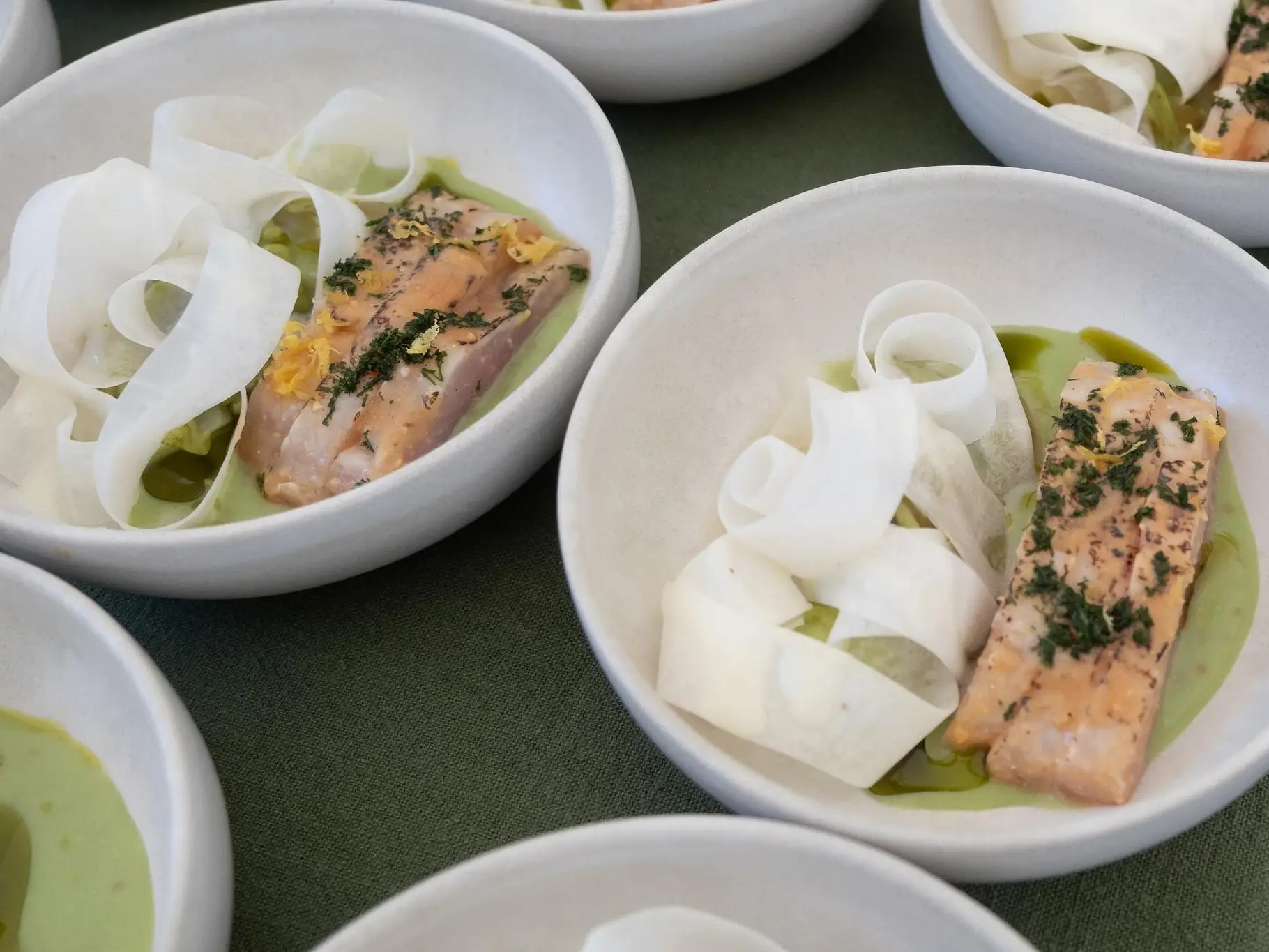 Angerichtete Schalen: Fisch auf grüner Sauce mit hauchdünnen Gemüsebändern
