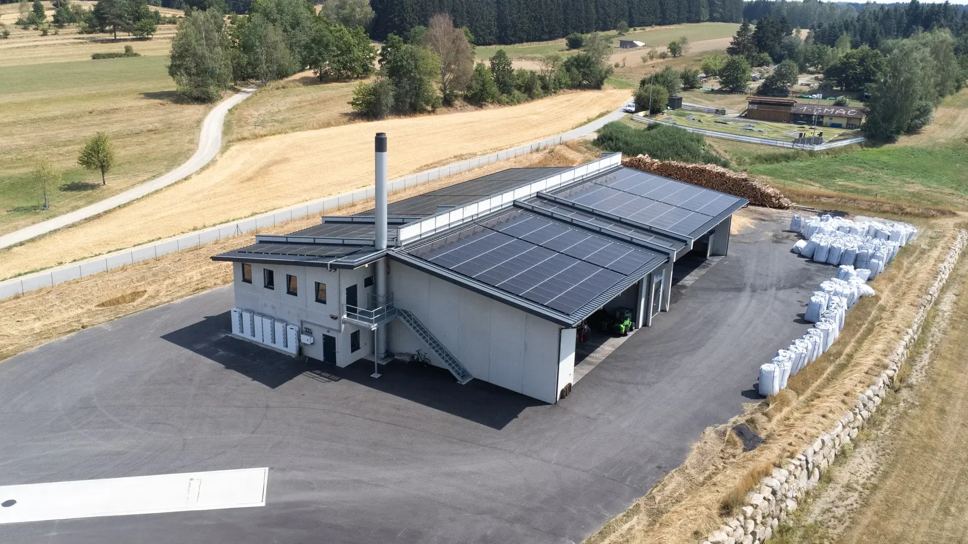 Luftaufnahme der W4K Nahwärme- und Pyrolyseanlage in Litschau mit Photovoltaikdach, Rundholzlager und Pflanzenkohle in Big Bags